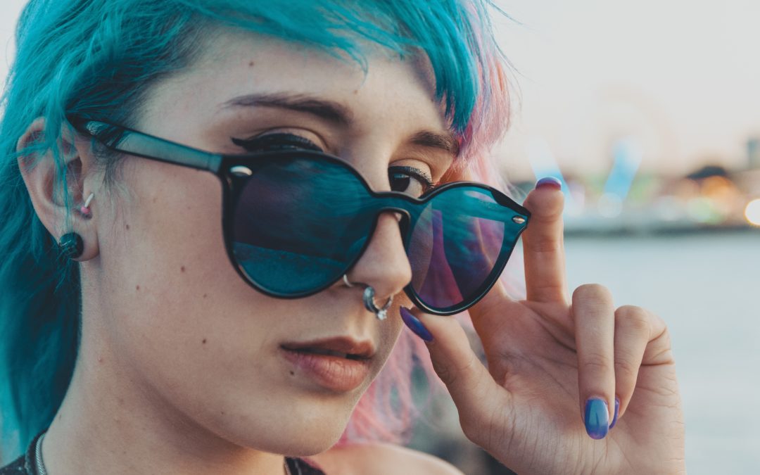A closeup shot of an attractive young blue-haired female wearing sunglasses